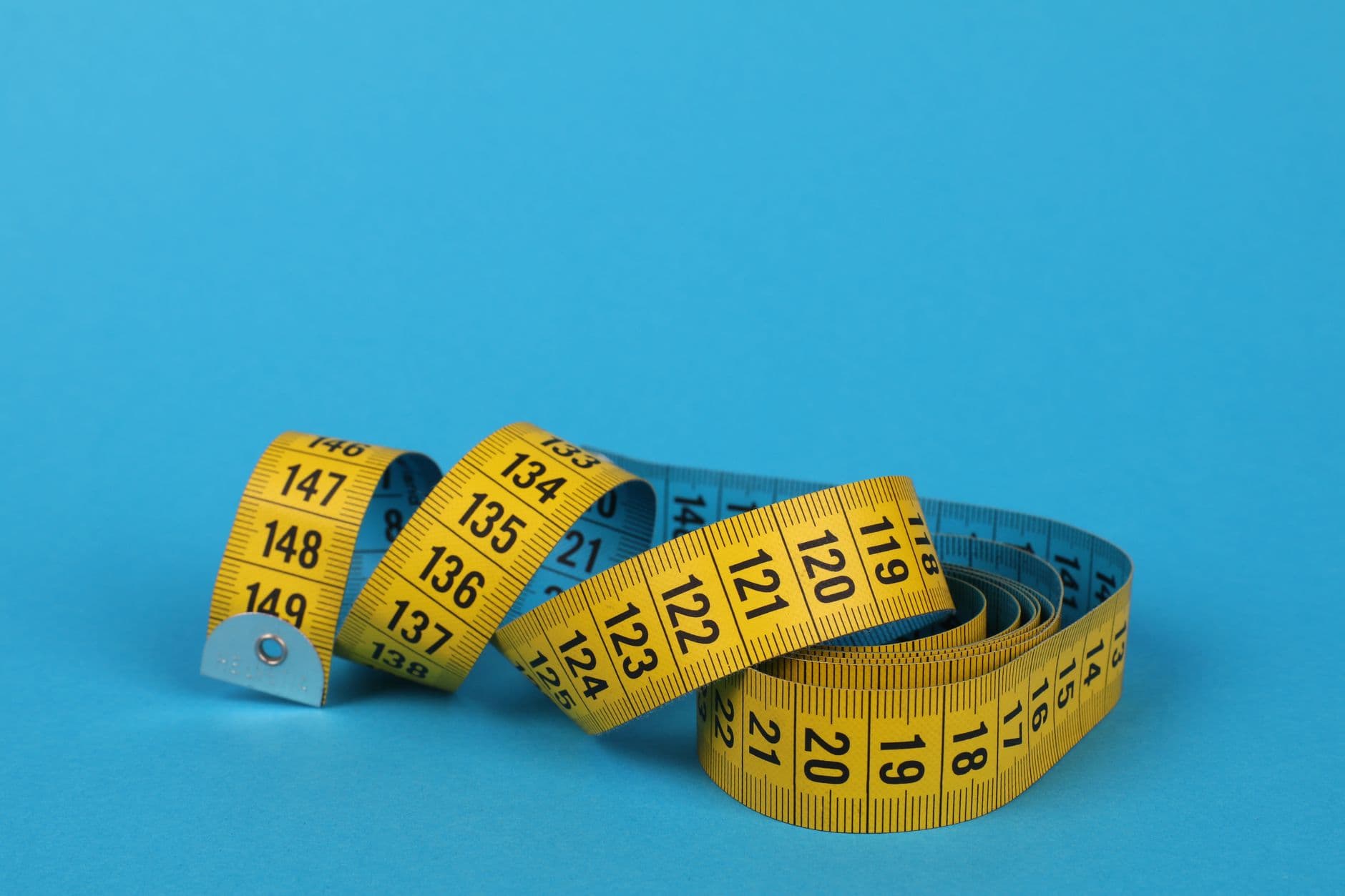 A tailor's measuring tape coiled on a blue ground