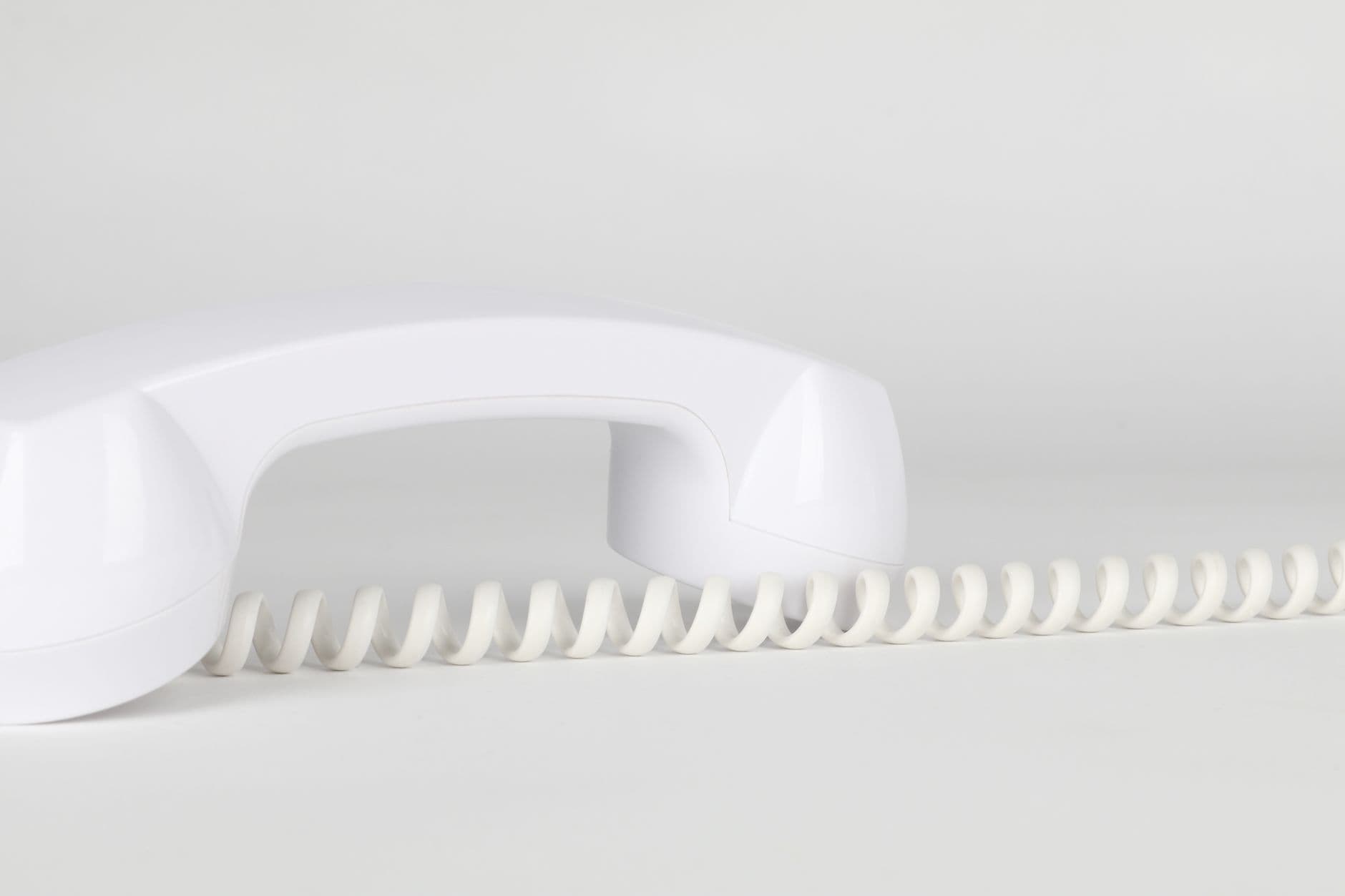 A white telephone handset and its coiled cord