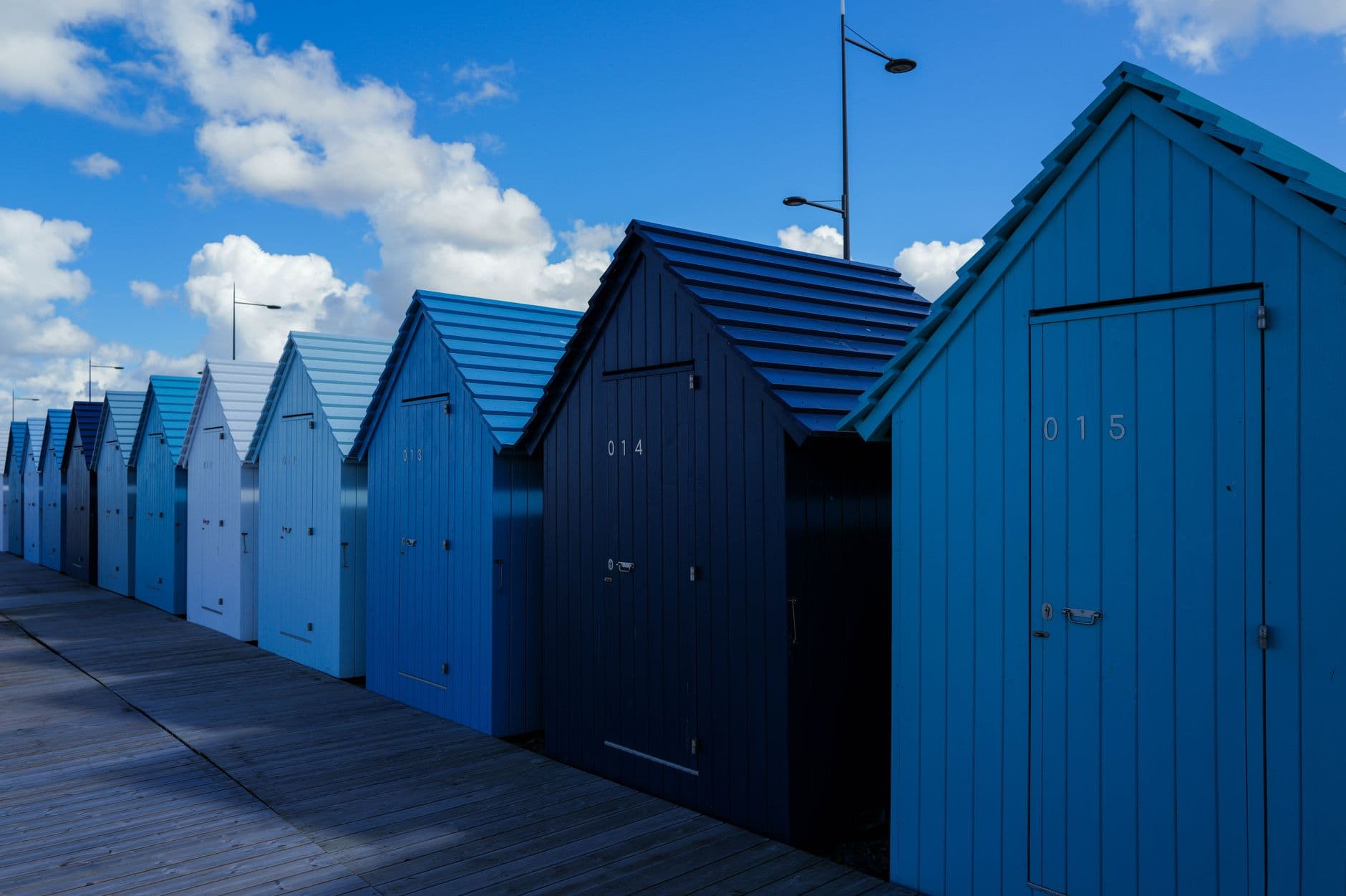 A row of numbered beach huts in blues