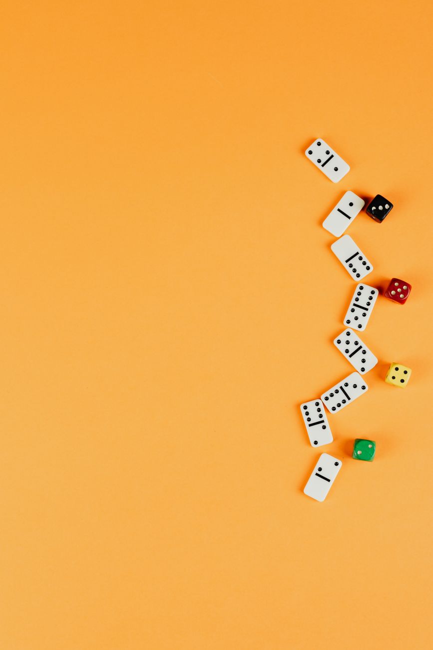 Dominoes and dice scattered on an orange surface