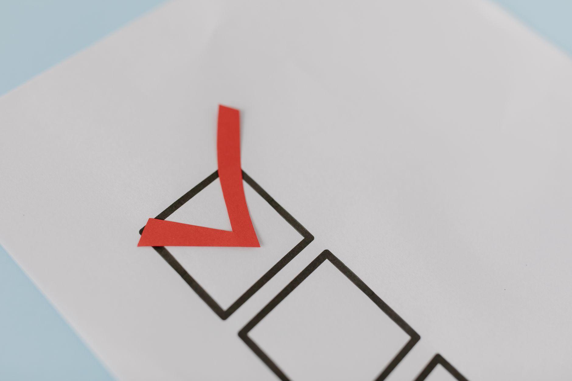 A red paper check mark in a printed box