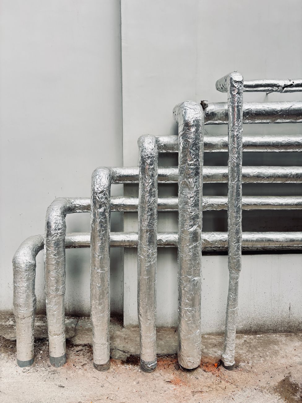 Insulated pipework stepping down an exterior wall