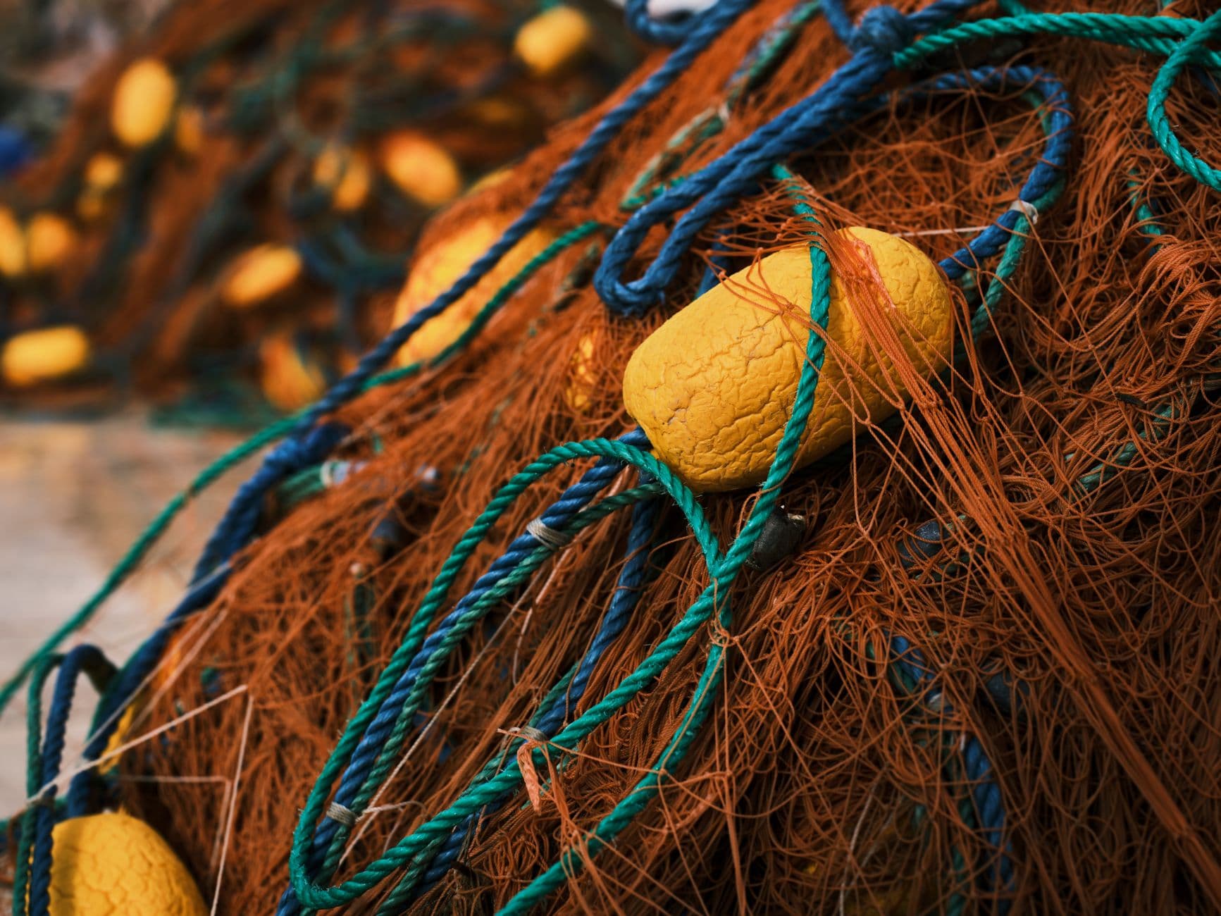 A fishing net with orange mesh and coloured rope